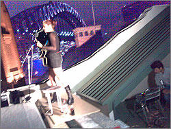 Photograph of singer on the roof of Gallery 26, with Sydney Harbour Bridge in the background