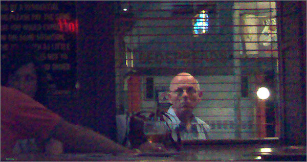 Photograph of man peering thru pub window (very indistinct)