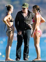 Photograph of Bono with two bikini-clad women