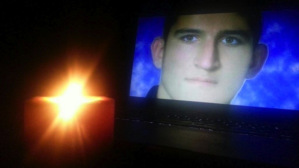 Photograph of Reza Berati on screen, with a candle in the foreground