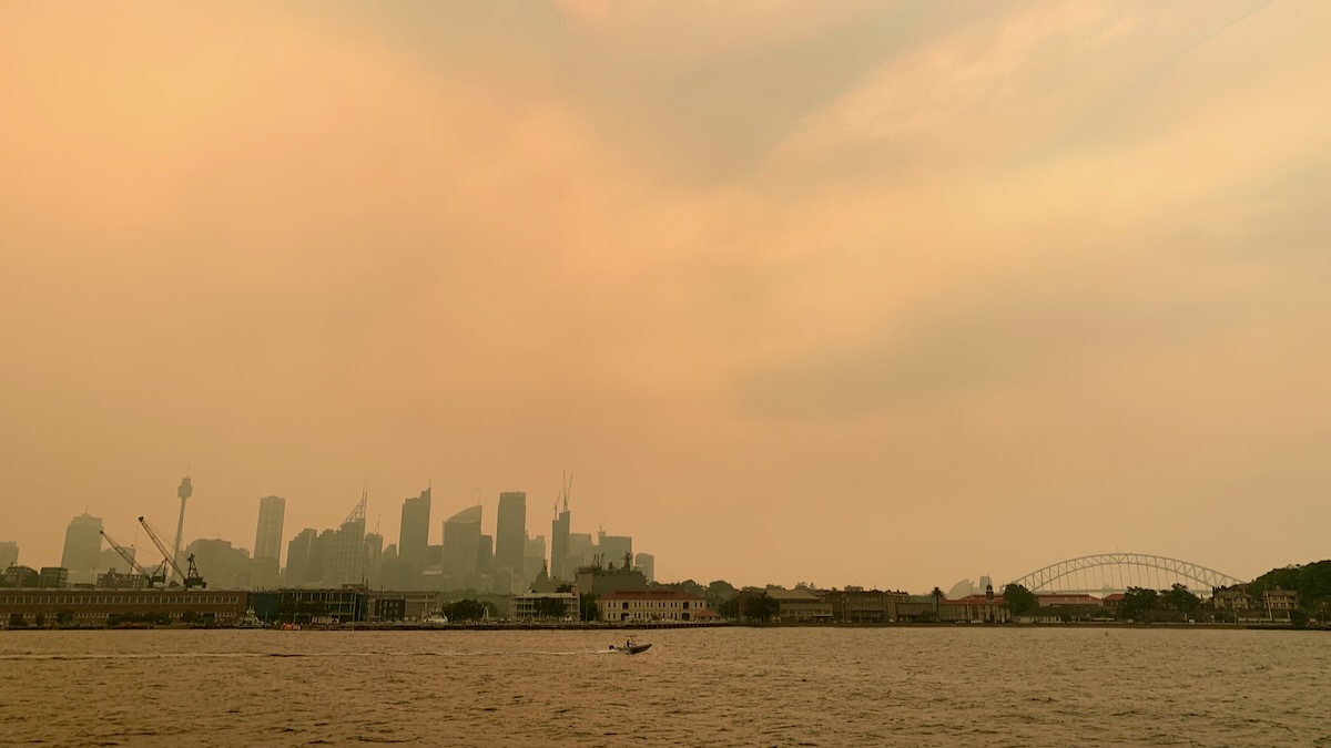 Under a grey and orange sky occupying most of the photograph is the Sydney skyline, made hazy and orange by the bushfire smoke.