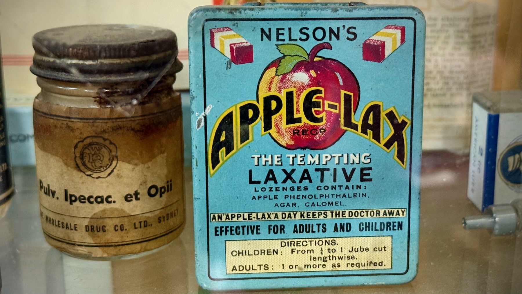 A small light-blue mental box with an apple logo and the words: Nelson’s Apple-Lax, The Tempting Laxative. Lozenges contain: apple, phenolphthalein, agar, calomel. An "Apple-Lax" a day keeps the doctor away. Effective for adults and children. Directions: Children: From 1/4 to 1 jube cut lengthwise. Adults: 1 or more as required.