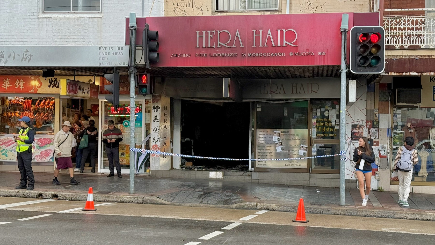 A typical row of Sydney suburban shops from around a century ago. Downstairs is a hair salon, Hera Hair, totally burned out. The area is cordoned off by police tape. On the right is a glass door leading to the business upstairs, Equiton Solicitors. On the left is a Chinese BBQ joint.
