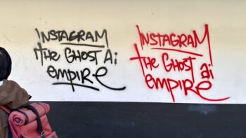 On a cream-coloured wall is scrawled in black the graffiti "Instagram the ghost AI empire", and the same again in red. On the left, a young man with a red backpack is disappearing out of frame.